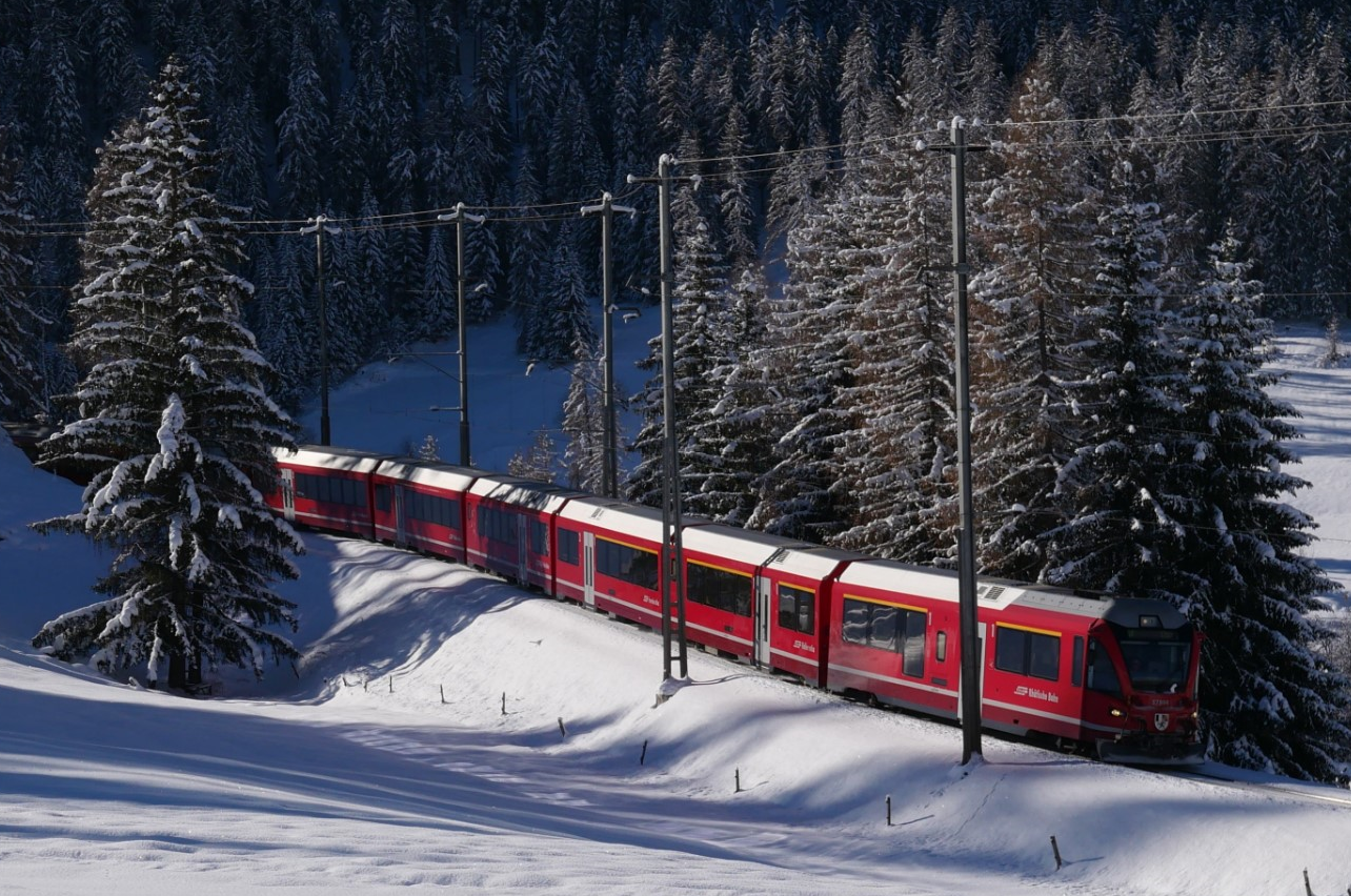 Ein roter Zug fährt durch eine verschneite Landschaft